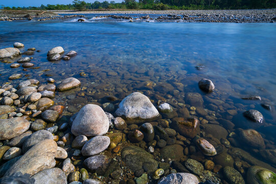Murti river in the morning, riverbed in foreground with flowing water and stones. Scenic beauty of Dooars landscape, West Bengal, India. Dooars is popular tourist destination for natural landscapes.