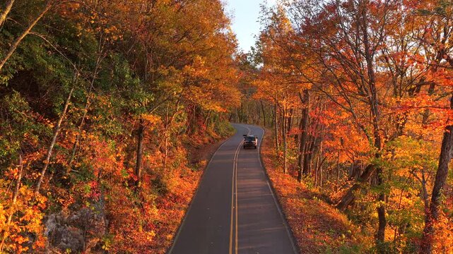 Car driving on mountain pass road between dense woods in seasonal colors in North Carolina. Blue Ridge Parkway in fall season.