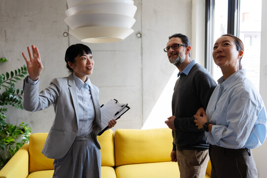 Professional real estate agent giving prospective buyers a guided tour of a modern apartment and explaining property features