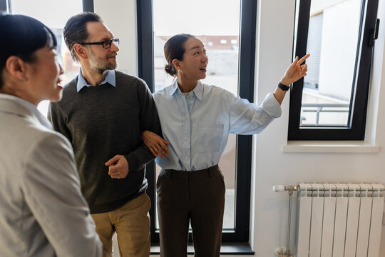 Professional real estate agent giving prospective buyers a guided tour of a modern apartment and explaining property features