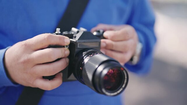 A person is holding a camera with a black body and a blue strap