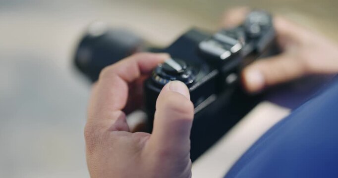 A person is holding a camera with a black body and a blue strap