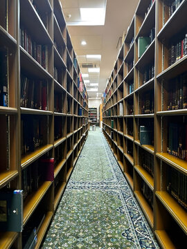 Narrow Aisle Between Tall Bookshelves in a Modern Library