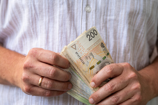 Male Hands Holding and Counting Stack of Polish 200 Zloty Currency Bills for Business Finance