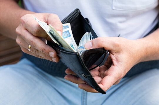 Close up of Man Hands Opening Black Wallet and Taking Polish 50 Zloty Bills for Shopping