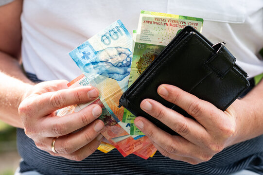 Close up of Man Hands Holding Open Wallet and Swiss Francs Banknotes Stack for Budget Concept