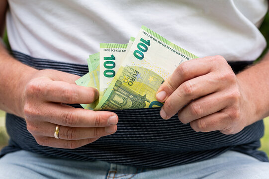 Close up of Man Hands Holding Stack of 100 Euro Banknotes for European Economy and Savings Concept
