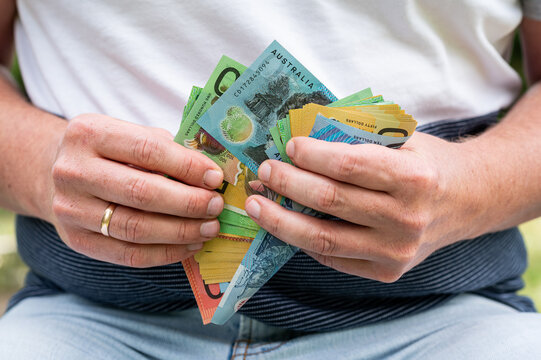 Close up of Man Hands Holding Fan of Australian Dollar Banknotes for Salary and Wealth Concept
