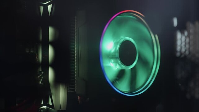 A green and purple computer fan is lit up. The fan is colorful and has a bright green center