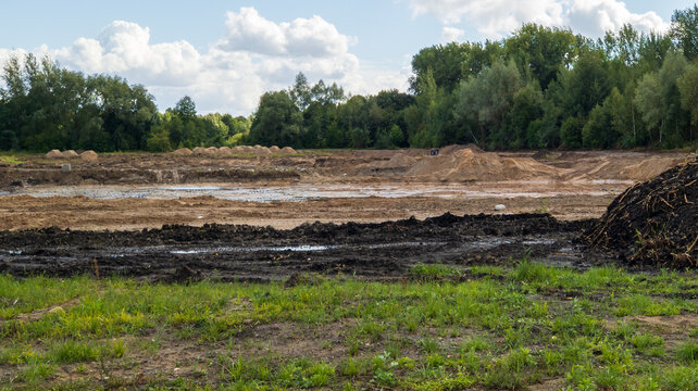 Leveled Construction Site with Excavated Soil Mounds surrounded by Forest. Land Preparation Concept