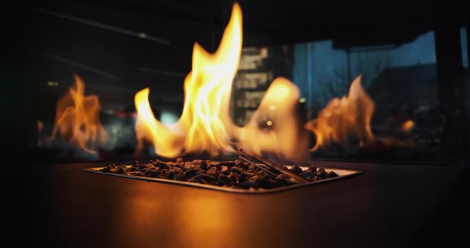 A fire is burning in a small heater container. The fire is orange and yellow. The container is made of metal