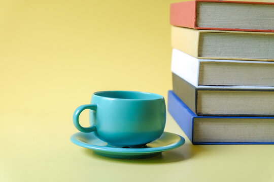 Coffee cup with stack of text books on background.