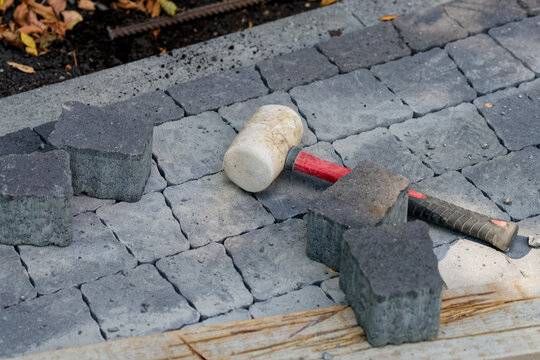 Close-up of a rubber hammer on newly laid paving stones, construction equipment used for aligning and installing pavement blocks Photo