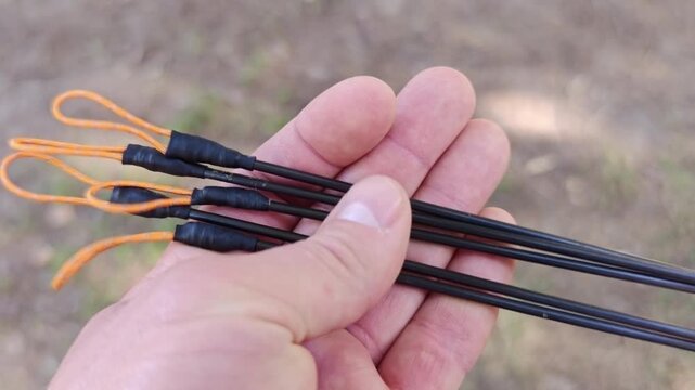 Hand holding ultralight carbon fiber tent stakes for camping