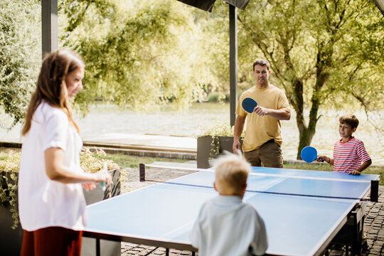 Family fun at the outdoor ping pong table beside a serene lake