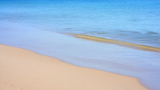 Slow motion pan tracking static shot of waves lapping and receding on sandy shoreline beach in calm sea