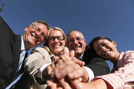 Diverse group of happy business colleagues stacking their hands together in a sign of unity outdoors