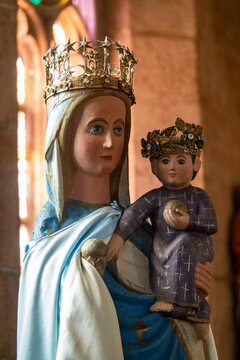 A painted wooden statue depicts the crowned Virgin Mary holding the crowned infant Jesus carrying an orb.