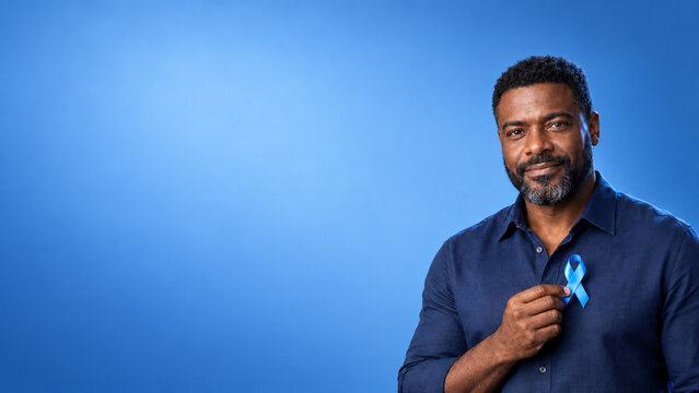 Portrait of a mature man holding a blue ribbon for prostate cancer awareness