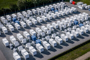 Obraz premium Aerial view of large-scale battery energy storage system (BESS) facility with grid infrastructure in Germany. Rows of containerized lithium-ion battery storage units at a utility-scale energy storage.