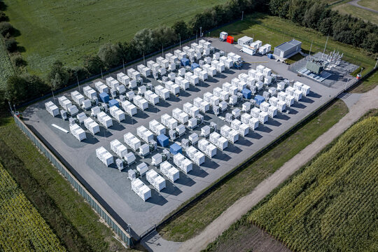 Aerial view of industrial large-scale battery storage facility for renewable energy grid stabilization by storing green electricity from wind and solar farms.