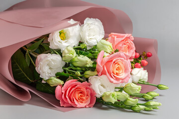 Obraz premium Bouquet of roses and eustoma wrapped in paper pink wrapper