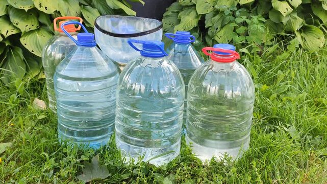 Large plastic water jugs repurposed for practical gardening tasks. 