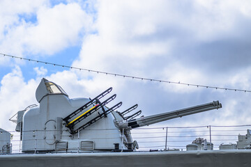 Historic naval gun turret on warship under cloudy sky. © Trygve