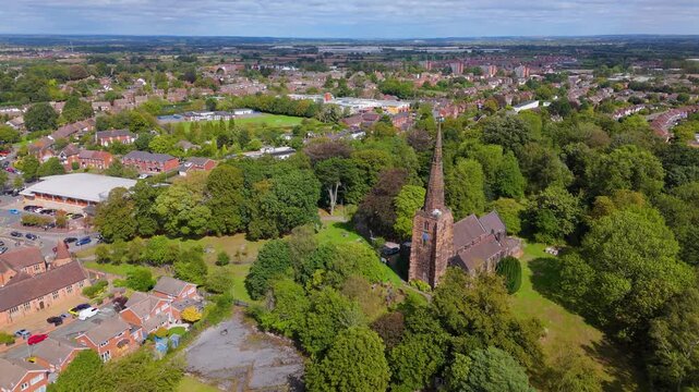 High aerial view of old parish church nestled in lush green trees