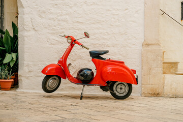 Classic Vespa scooter stands beside a limestone wall in Locorotondo, Italy. The image reflects freedom, heritage, mobility and Mediterranean lifestyle © Анна Зеленая