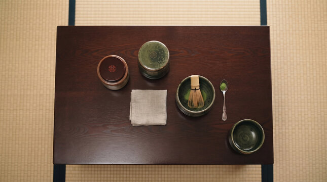 Traditional Japanese Tea Ceremony Utensils including Matcha Bowl and Whisk on Wooden Table over Tatami Mat