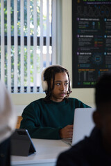 Classmates with teen African American male sitting at desk, wearing white headphones, using laptop © WavebreakMediaMicro