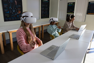 Three teenage students wearing white VR headsets while using silver laptops at lab table © WavebreakMediaMicro