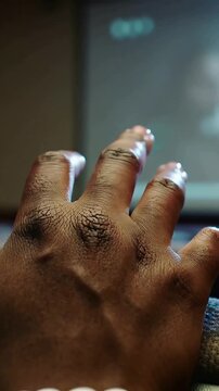 Vertical video: Moving hand extending fingers at screen as projector lighting masked host and LED