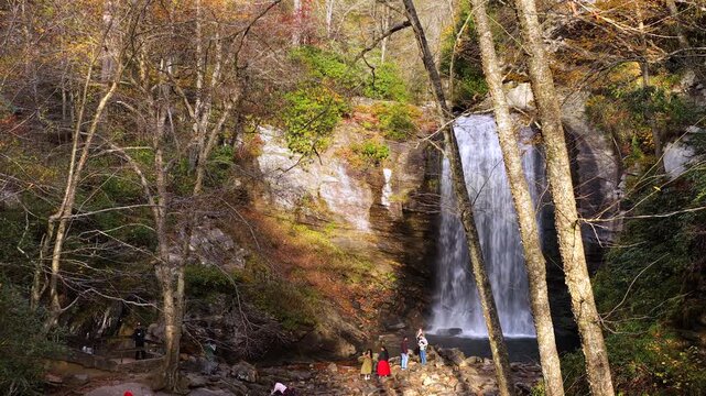 Mountain forest waterfall during peak fall season. Observation deck and staircase overlook cascade surrounded by brilliant autumn foliage.