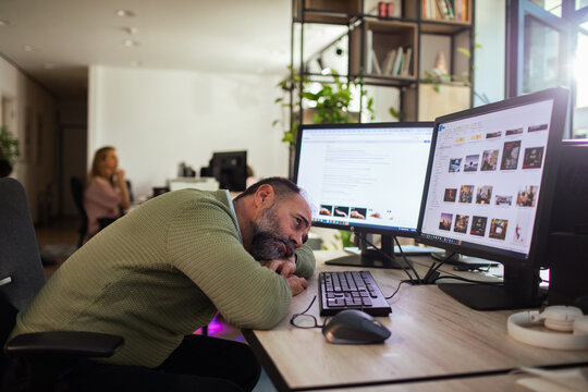 Tired office worker resting at computer desk in open office