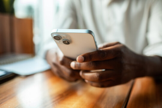 Close-up of hands using smartphone at wooden table