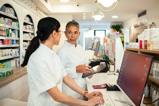 Two pharmacists discussing prescriptions at pharmacy counter