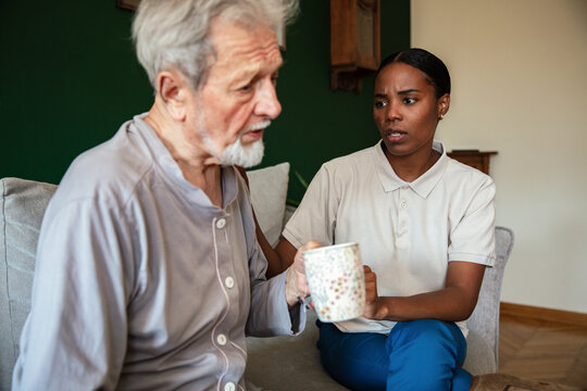 Caregiver supporting elderly man at home