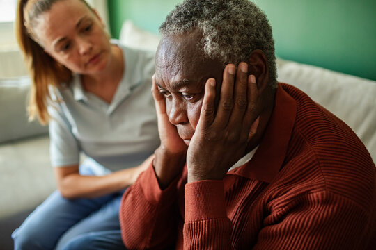 Caregiver comforting worried senior man at home