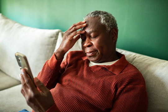 Senior man stressed while using smartphone at home