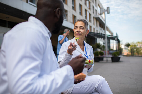 Medical colleagues eating healthy lunch outside hospital
