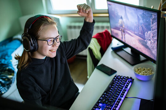 Smiling teen girl celebrating pc gaming victory at home
