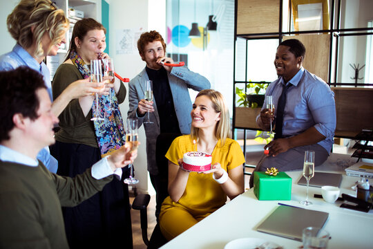 Happy coworkers celebrating birthday in modern office