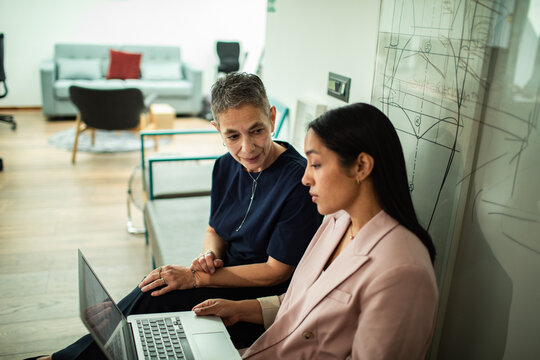 Two professionals collaborating on a laptop in a creative office