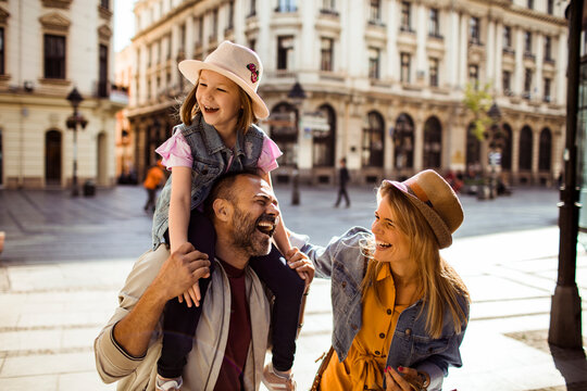 Happy parents with daughter walking on historic city street