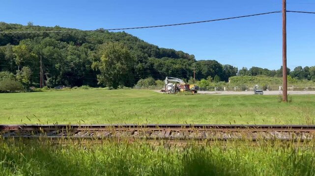 Tracking shot alongside empty railway tracks passing a grassy field