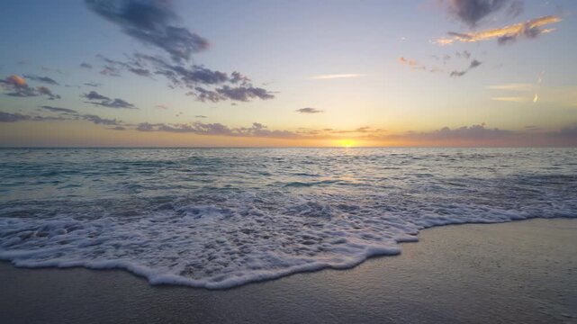 Panoramic coastal view of Atlantic Ocean during sunset. Vivid orange and blue sky over calm water. Peaceful tropical scenery and vacation mood.