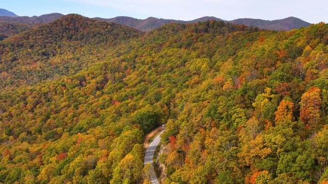 Peaceful roadside overlook in Tennessee Appalachians with parked car facing vibrant autumn scenery and endless forested mountain ridges.