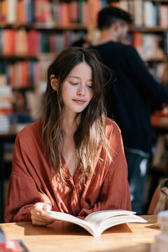 Woman reading an open book in a bookstore quiet candid portrait with warm sunlight for lifestyle background